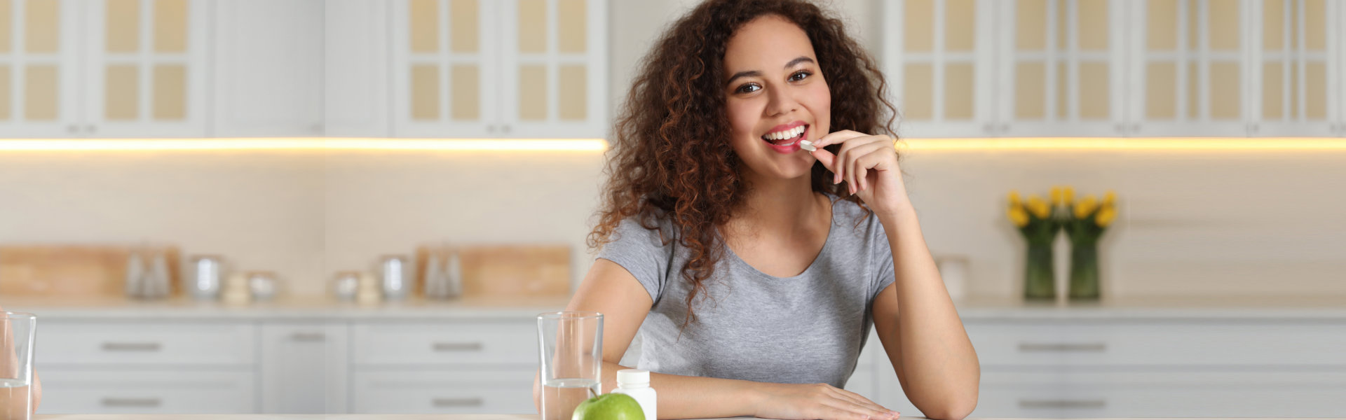 woman taking vitamin pill in kitchen